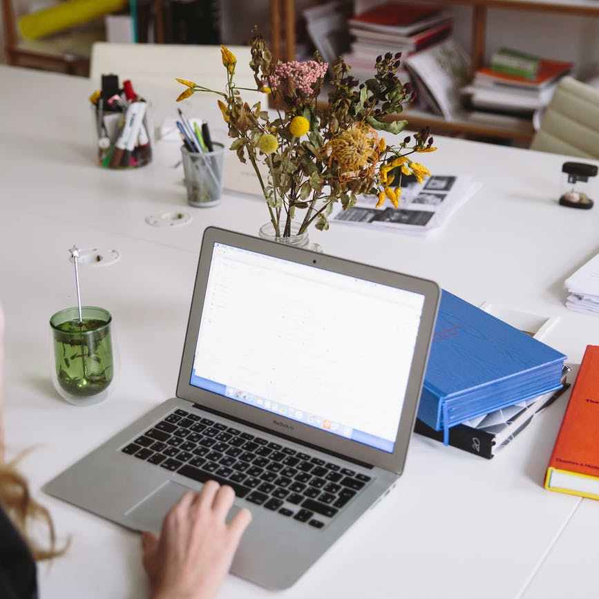 person typing on a laptop on white table